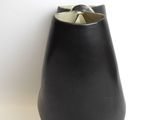 a black vase with a white top sitting on a white surface