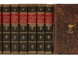 six vieux livres sont alignés sur une surface blanche