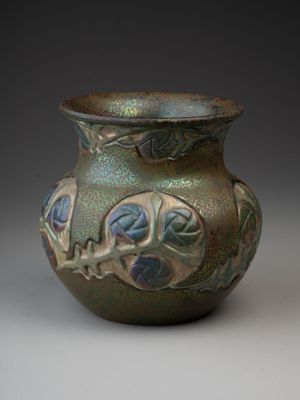 un vase vert orné de motifs bleus et verts