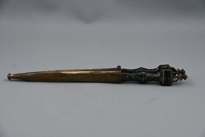 un vieux stylo en laiton avec un manche en bois posé sur une surface blanche