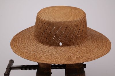 un chapeau de paille posé sur un support en bois