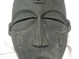 un masque noir orné d'une croix, posé sur un drap blanc