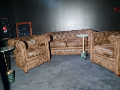 un canapé et un fauteuil dans une pièce où se trouve un tableau noir accroché au mur