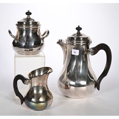 deux théières en argent et une cafetière posées sur une table