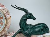 a statue of an antelope sitting next to a clock