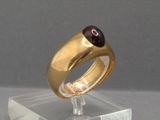 une bague en or surmontée d'une pierre rouge