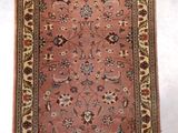 Le tapis qui recouvre le sol est rouge et beige, avec une bordure dorée.