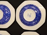 four plates with blue and white designs on them on a black surface