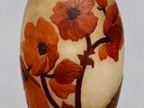un vase avec des fleurs peintes dessus, posé sur une table