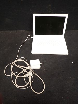 un ordinateur portable blanc posé sur une table, avec son chargeur branché
