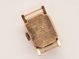a close up of a gold plated watch on a white surface