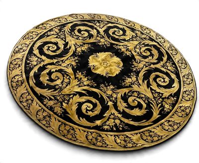 une assiette noire et dorée ornée de motifs dorés