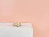 Une bague en or sertie d'un seul diamant repose sur un bloc de marbre