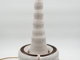 white ceramic table lamp with a brown base and a light bulb on top of it