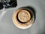 a brown vase sitting on top of a table next to a pair of scissors