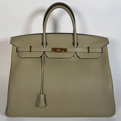 un sac à main en cuir beige avec des finitions dorées sur la poignée