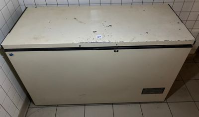 a small white refrigerator in the corner of a tiled room
