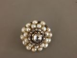 un gros plan d'une bague en perle et diamant posée sur une table