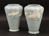 deux vases décorés de cygnes, posés sur une table