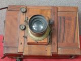 un vieil appareil photo en bois posé sur un tissu rouge
