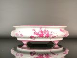 un bol blanc orné de fleurs roses, posé sur une table