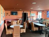 tables and chairs in a restaurant with orange walls and wood floors