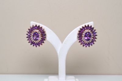 pair of amethorate and goldtone earrings on a white stand