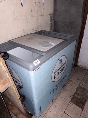 a blue refrigerator sitting in the corner of a room next to a pile of wood