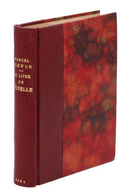 an old book with a red cover sitting on top of a white surface