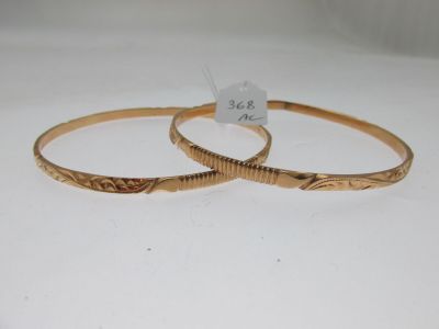 deux bracelets rigides en or, ornés de motifs gravés sur un fond blanc