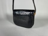 a black crocodile skin purse with a gold clasp