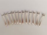 six forks are arranged in a row on a white surface