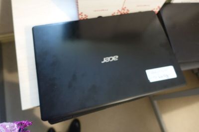 a black laptop sitting on a table with a purple flower
