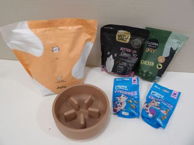 un bol de nourriture pour chat, un sachet d'herbe à chat et un autre sachet d'herbe à chat posés sur un plan de travail