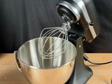 a metal bowl with a whisk inside of it on a wooden table