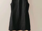 a black dress hanging on a wall next to a wooden hanger