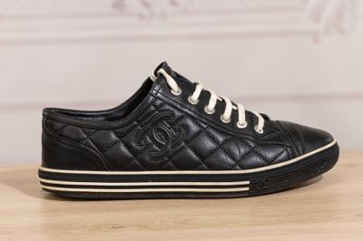 a black leather sneaker with white laces on a wooden table