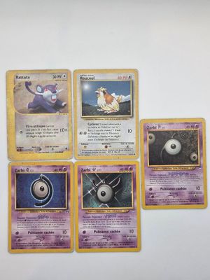 Plusieurs cartes Pokémon sont posées sur une surface blanche, sur fond blanc.