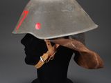an old helmet on a mannequin head with a red arrow painted on it