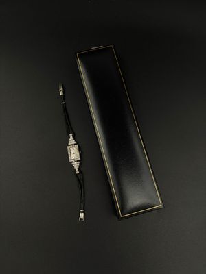 une montre et un stylo posés sur une surface noire