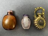 Trois bouteilles en verre et une bouteille plaquée laiton sont posées sur une table