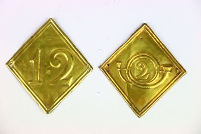 deux insignes métalliques dorés portant le chiffre « 1 » et le chiffre « 1 »