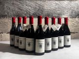 bottles of wine are lined up on a table in front of a stone wall