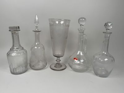 cinq bouteilles en verre et un verre à vin posés sur une table