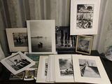 Plusieurs photographies en noir et blanc sont posées sur une table près d'un mur.