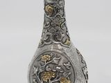 an image of a silver vase with a gold decoration on it
