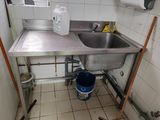 une cuisine avec un évier et un seau posé par terre