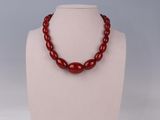 a close up of a necklace with red beads on a mannequin