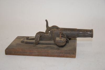 an old gun on a wooden block on a white surface