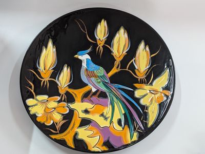 a plate with a bird painted on it sitting on a table